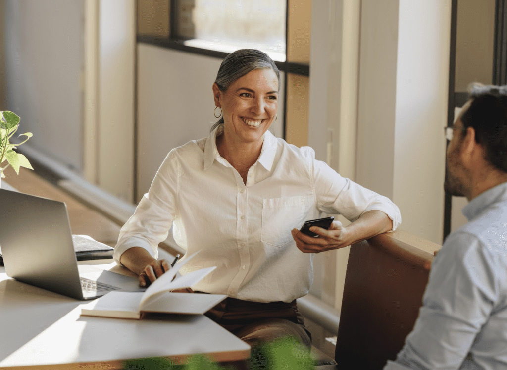 Two Contract Advance employees sat at a desk having a conversation and smiling.