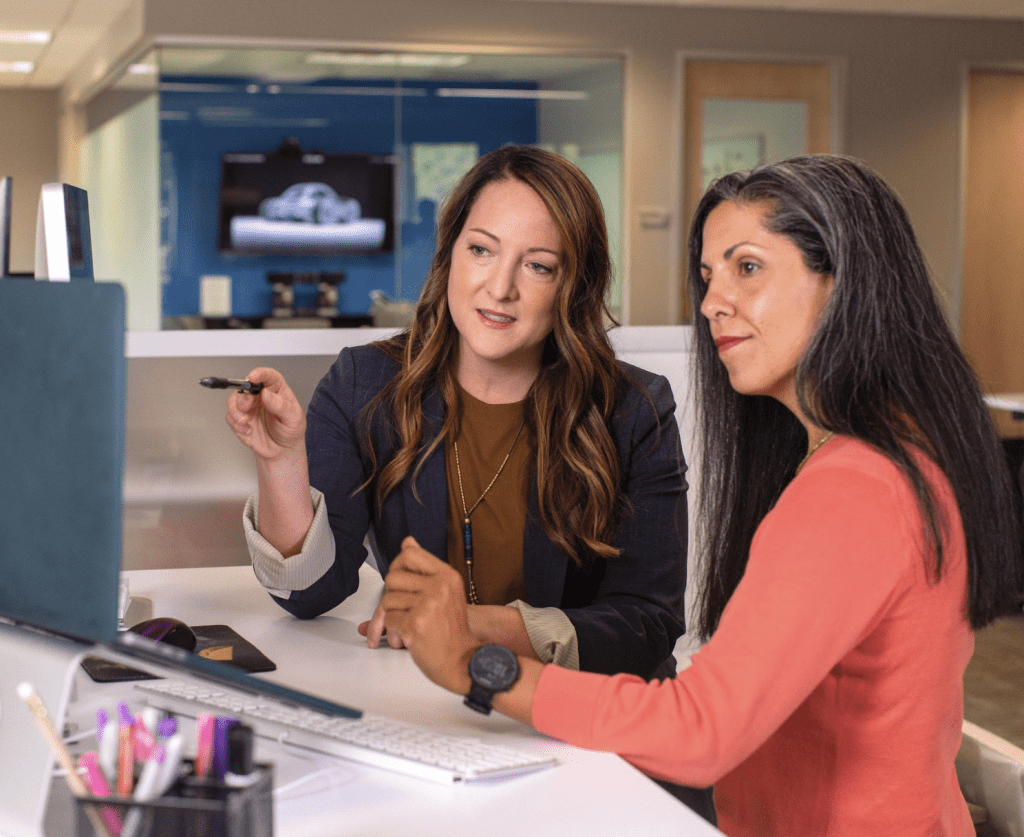 Two smartly dressed Contract Advance employees sat at a desk working from the same computer.