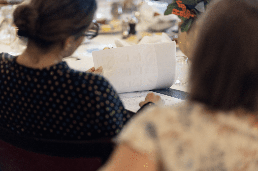 The back of two women sat at a dinner table looking at a menu.